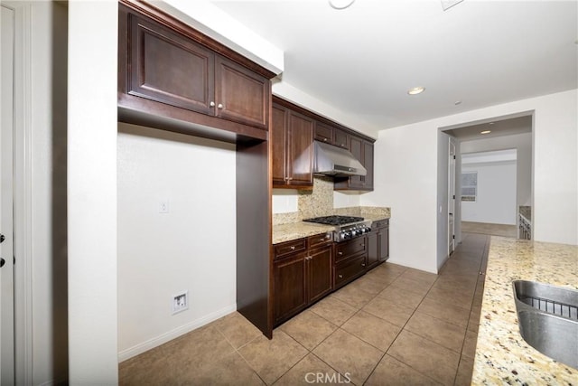 22364 Driftwood Ct, Saugus, CA 91350 - kitchen with stainless steel gas cooktop, under cabinet range hood, light stone counters, a sink, and decorative backsplash
