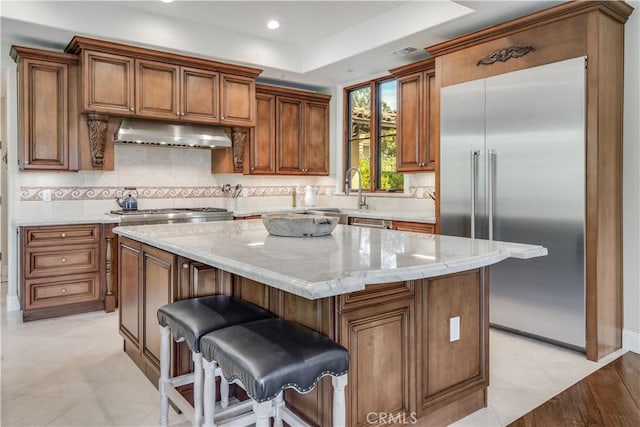 1217 Granvia Altamira, Palos Verdes Estates, CA 90274 - kitchen featuring a sink, appliances with stainless steel finishes, under cabinet range hood, brown cabinets, and backsplash