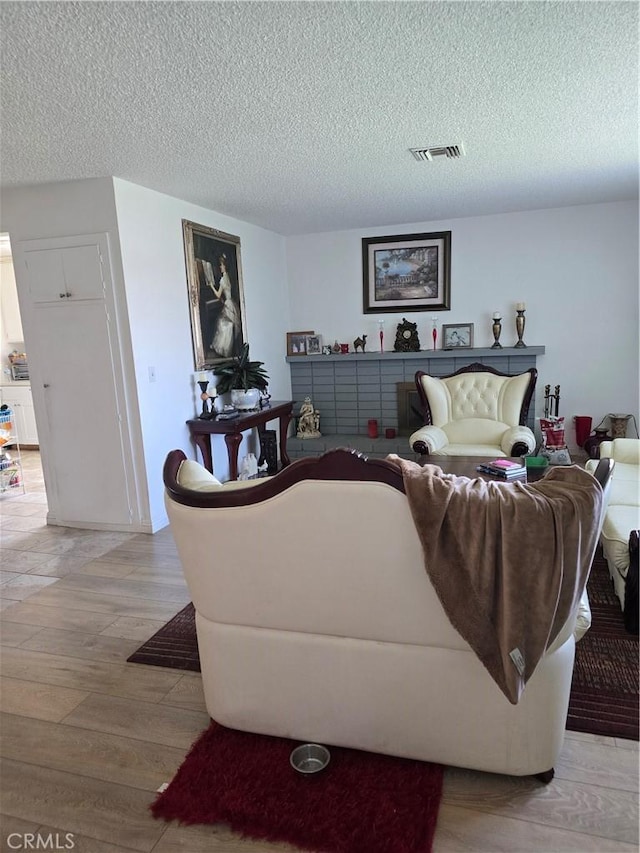 1861 N Lilac Ave, Rialto, CA 92376 - living area with light wood-style flooring, a textured ceiling, and visible vents