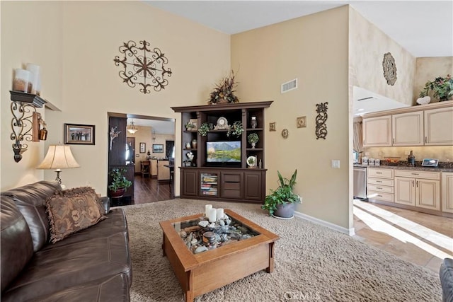 living room featuring baseboards, a towering ceiling, and visible vents