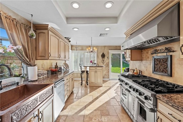 kitchen with stainless steel appliances, stone tile floors, visible vents, wall chimney range hood, and a raised ceiling