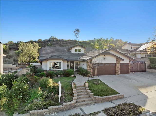 view of front facade with a gate, driveway, a tiled roof, an attached garage, and fence