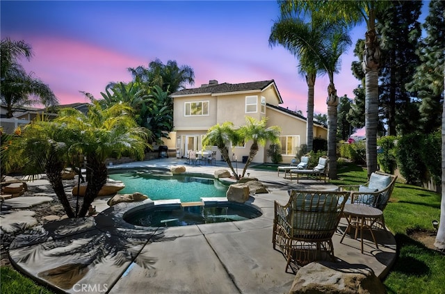 pool at dusk featuring a patio area and a pool with connected hot tub