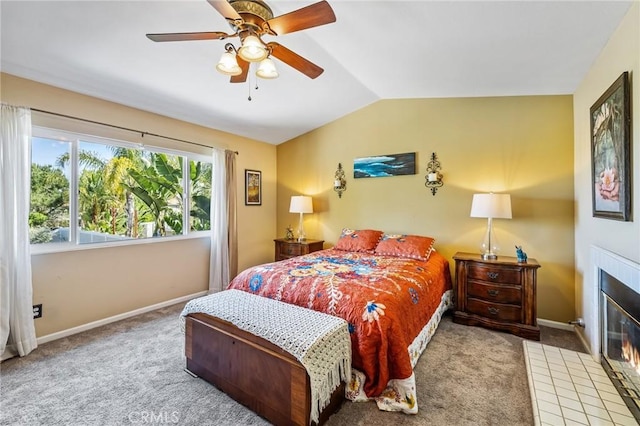 carpeted bedroom with baseboards, a ceiling fan, vaulted ceiling, and a fireplace