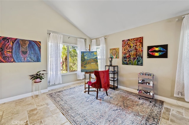 sitting room featuring stone tile flooring, baseboards, and vaulted ceiling
