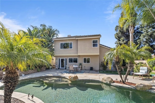 back of house featuring an outdoor pool, a patio area, and stucco siding