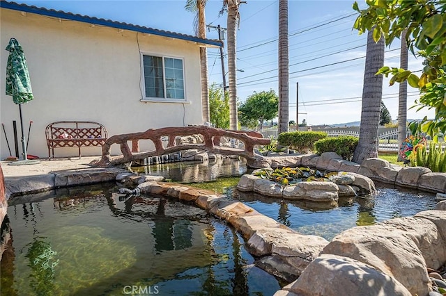exterior space featuring a small pond and fence