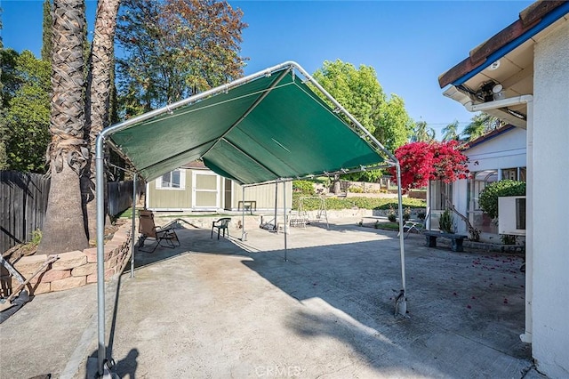 view of patio with fence, a shed, and an outbuilding