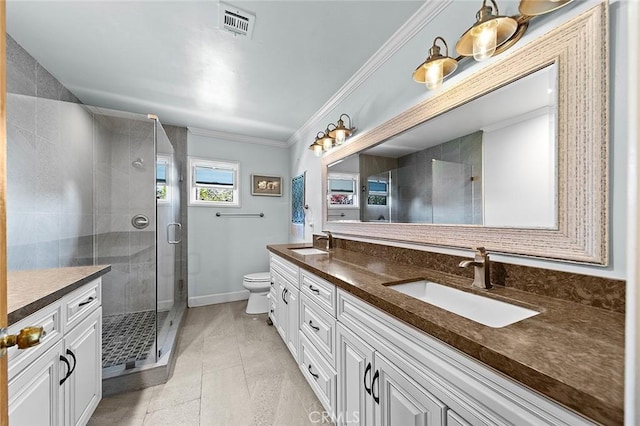 full bath featuring toilet, a stall shower, double vanity, and a sink
