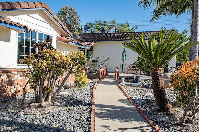 exterior space featuring stucco siding and a tiled roof