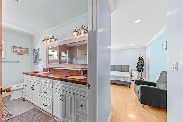 ensuite bathroom with double vanity, ensuite bathroom, ornamental molding, and a sink