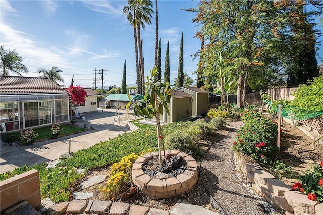 view of yard featuring an outdoor fire pit, fence, a shed, and an outbuilding
