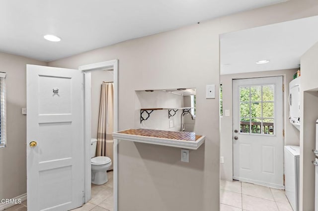 23624 Scenic Dr, Crestline, CA 92325 - laundry area featuring stacked washer and clothes dryer, light tile patterned floors, and baseboards