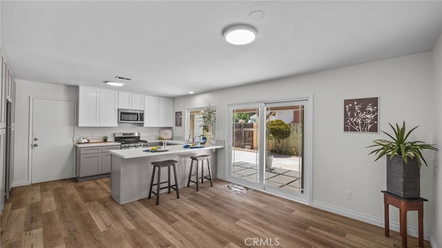 10069 Hershey Way, Riverside, CA 92503 - kitchen with stainless steel appliances, a breakfast bar area, a peninsula, wood finished floors, and light countertops