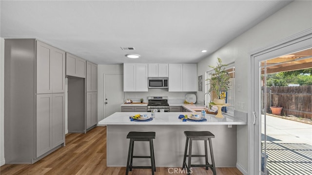 10069 Hershey Way, Riverside, CA 92503 - kitchen featuring stainless steel appliances, a peninsula, light countertops, light wood-style floors, and recessed lighting