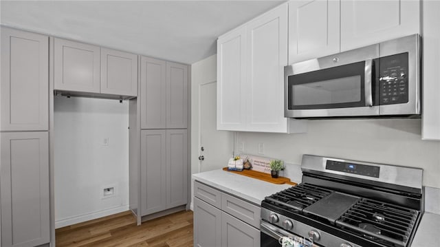 10069 Hershey Way, Riverside, CA 92503 - kitchen with appliances with stainless steel finishes, light wood-style flooring, light countertops, and white cabinetry