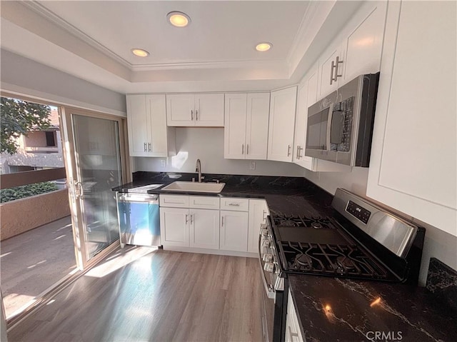 17114 Bluewater Ln Unit 141, Huntington Beach, CA 92649 - kitchen featuring appliances with stainless steel finishes, a sink, white cabinets, a tray ceiling, and light wood-type flooring