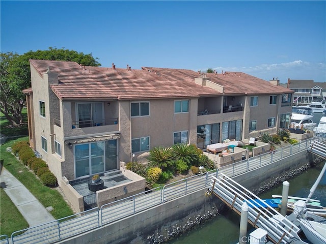 17114 Bluewater Ln Unit 141, Huntington Beach, CA 92649 - rear view of house featuring a balcony, a fenced backyard, stucco siding, and a water view