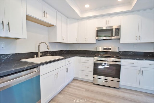 17114 Bluewater Ln Unit 141, Huntington Beach, CA 92649 - kitchen featuring appliances with stainless steel finishes, a sink, a tray ceiling, recessed lighting, and white cabinetry