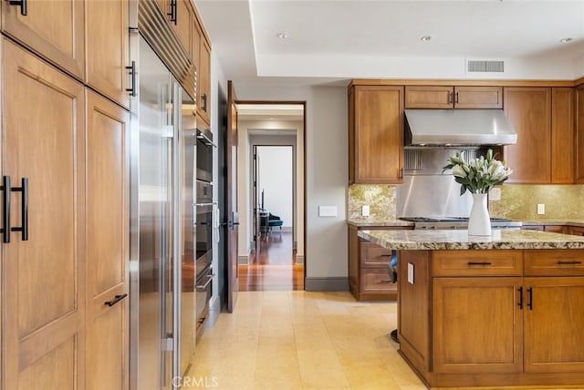 kitchen with under cabinet range hood, visible vents, brown cabinets, and appliances with stainless steel finishes