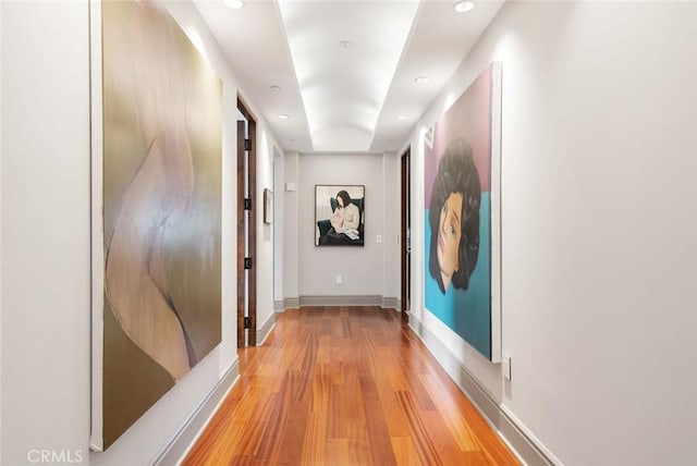corridor featuring light wood-style flooring, baseboards, and recessed lighting
