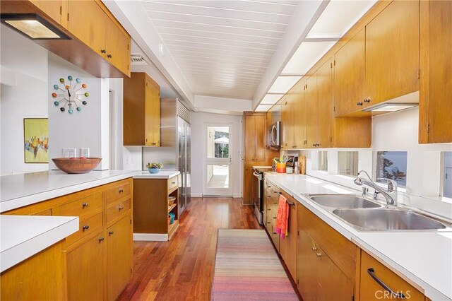 kitchen featuring dark wood-style flooring, light countertops, a sink, and appliances with stainless steel finishes