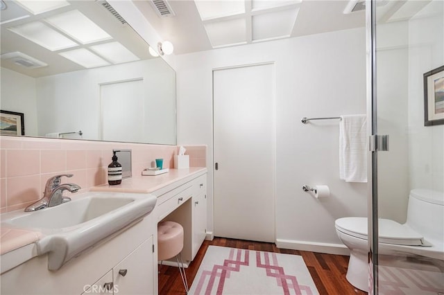 bathroom with vanity, visible vents, toilet, wood finished floors, and backsplash