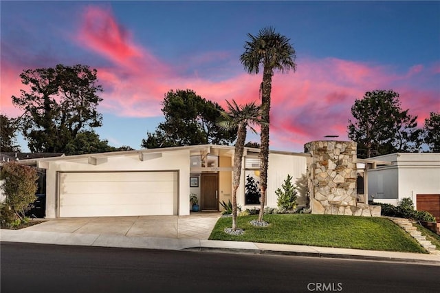 view of front of house featuring driveway, a front lawn, a garage, and stucco siding
