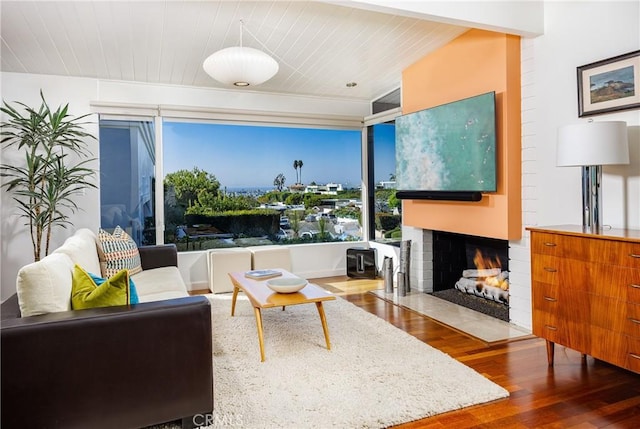 living area with a fireplace with flush hearth, wood ceiling, and wood finished floors