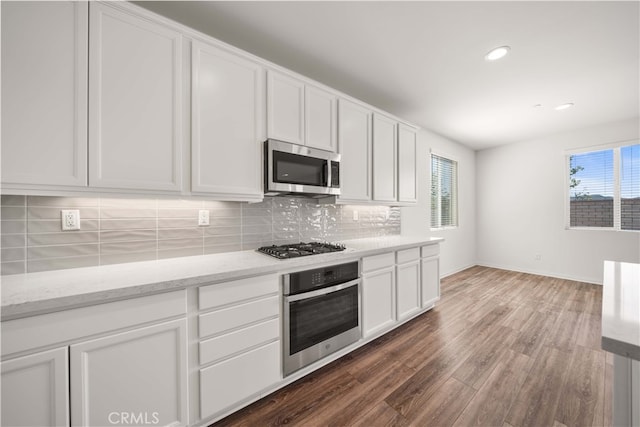 29391 Santa Ynez Cir, Menifee, CA 92584 - kitchen featuring dark wood-style flooring, white cabinetry, light stone countertops, decorative backsplash, and stainless steel appliances