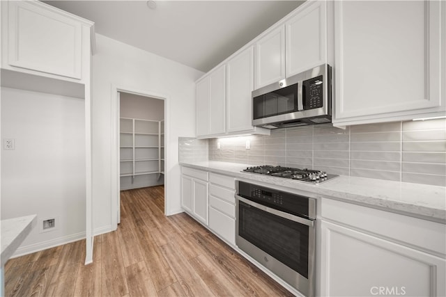 29391 Santa Ynez Cir, Menifee, CA 92584 - kitchen featuring visible vents, white cabinets, light wood-style floors, stainless steel appliances, and decorative backsplash