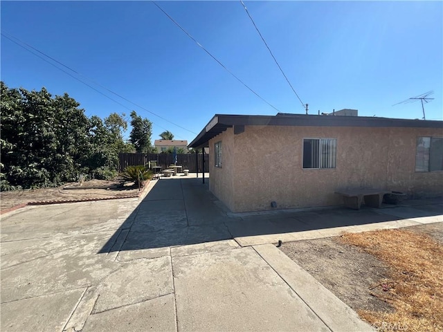 view of side of property with a patio, stucco siding, and fence
