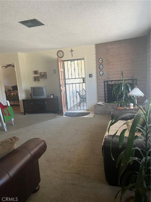living area with visible vents, carpet, a fireplace, and a textured ceiling