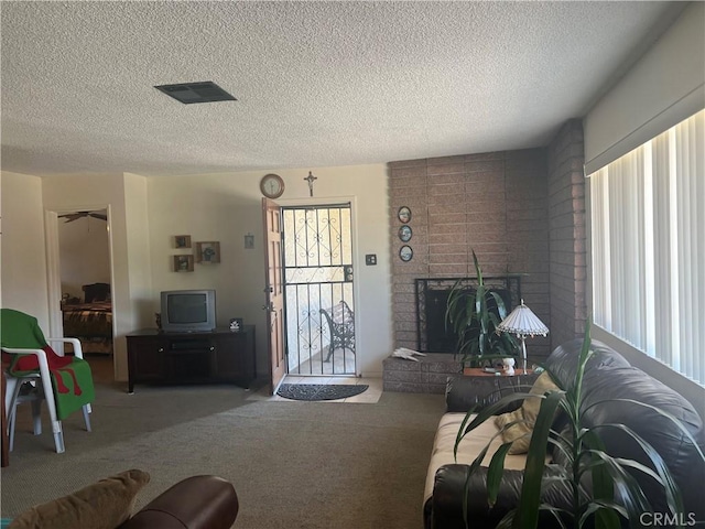 living area with a fireplace, carpet flooring, visible vents, and a textured ceiling