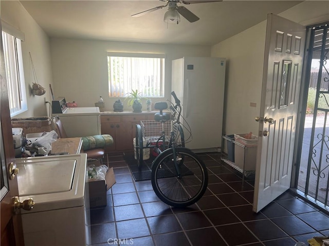 interior space with dark tile patterned floors, washer / dryer, and a ceiling fan