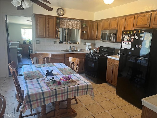 kitchen with tasteful backsplash, light tile patterned flooring, a sink, and black appliances