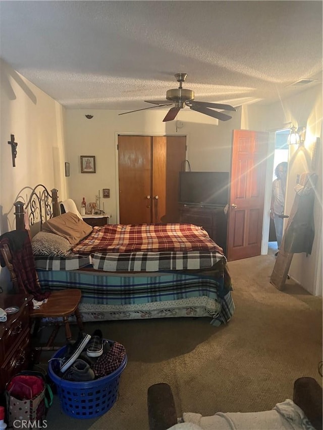 carpeted bedroom featuring a textured ceiling, a closet, and a ceiling fan