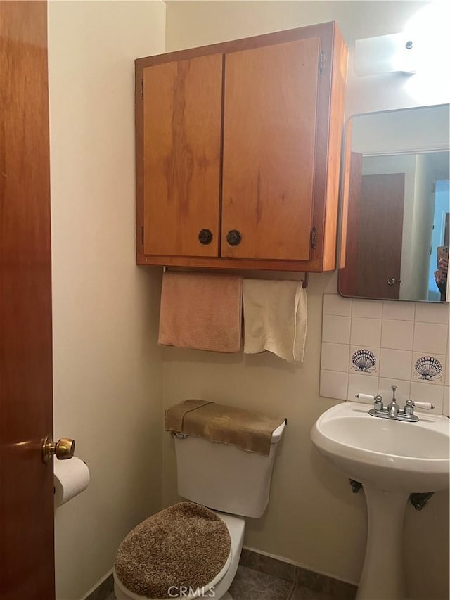 bathroom with tile patterned floors, tasteful backsplash, baseboards, and toilet
