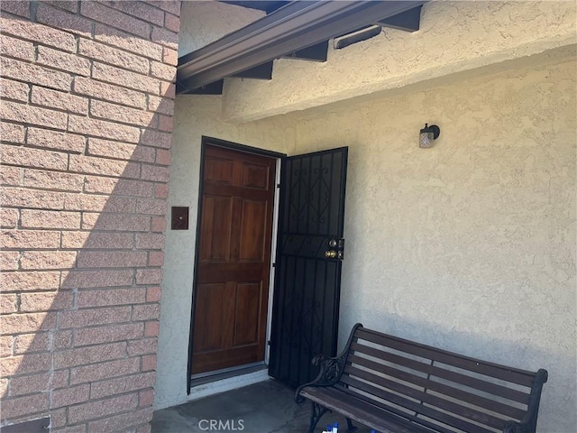 entrance to property featuring brick siding and stucco siding