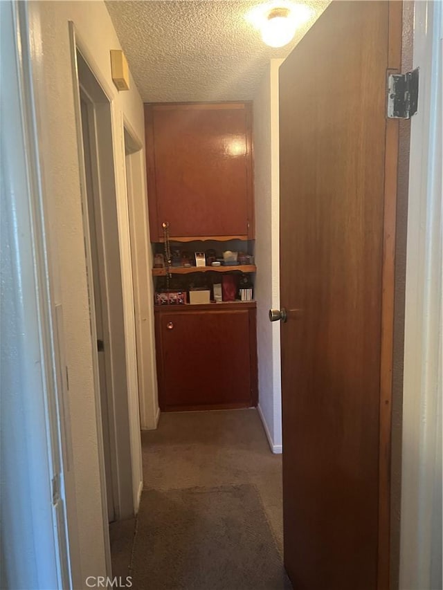 hallway with light carpet and a textured ceiling