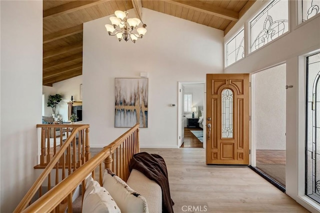 entrance foyer featuring light wood finished floors, wooden ceiling, high vaulted ceiling, and a chandelier