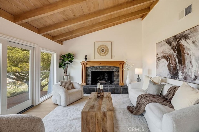 living room with a tile fireplace, wood finished floors, visible vents, vaulted ceiling with beams, and wood ceiling