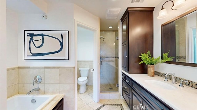 bathroom featuring a stall shower, toilet, tile patterned flooring, a garden tub, and vanity