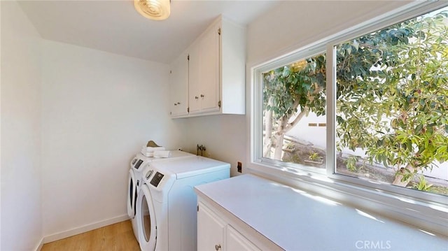 washroom with cabinet space, light wood-style floors, baseboards, and washer and dryer