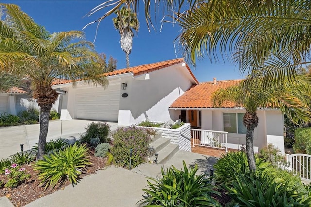 mediterranean / spanish house featuring an attached garage, a tile roof, concrete driveway, and stucco siding