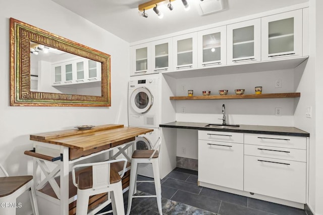 1417 Foothill Rd, Ojai, CA 93023 - washroom with stacked washing machine and dryer, a sink, dark tile patterned flooring, and rail lighting