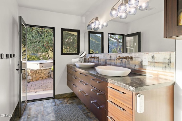 1417 Foothill Rd, Ojai, CA 93023 - full bath with a chandelier, baseboards, double vanity, stone finish floors, and tasteful backsplash