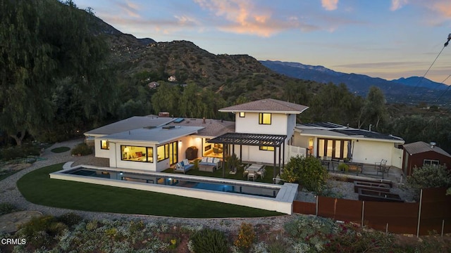 1417 Foothill Rd, Ojai, CA 93023 - back of property at dusk featuring a mountain view, an outdoor pool, a yard, stucco siding, and an outdoor living space