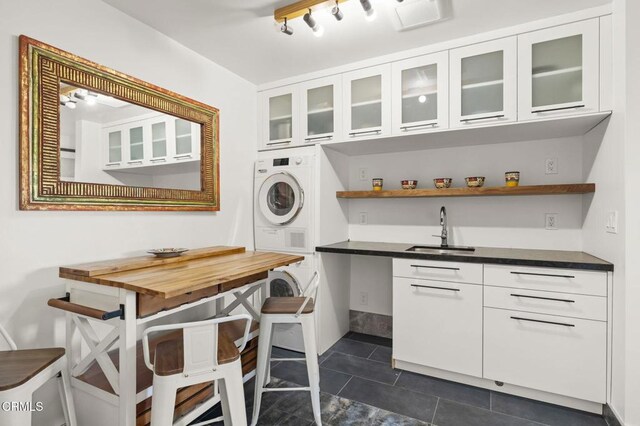 1417 Foothill Rd, Ojai, CA 93023 - laundry room featuring estacked washer and dryer, a sink, dark tile patterned flooring, and rail lighting