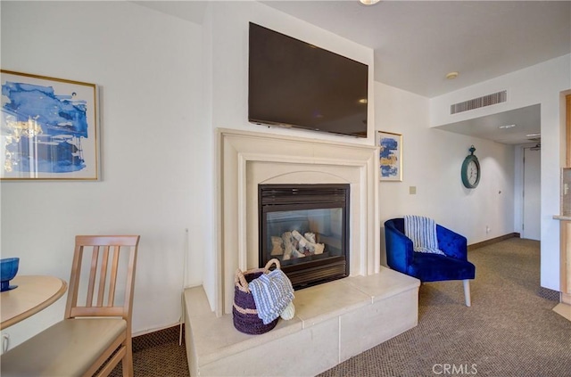 carpeted living area with a glass covered fireplace, visible vents, and baseboards